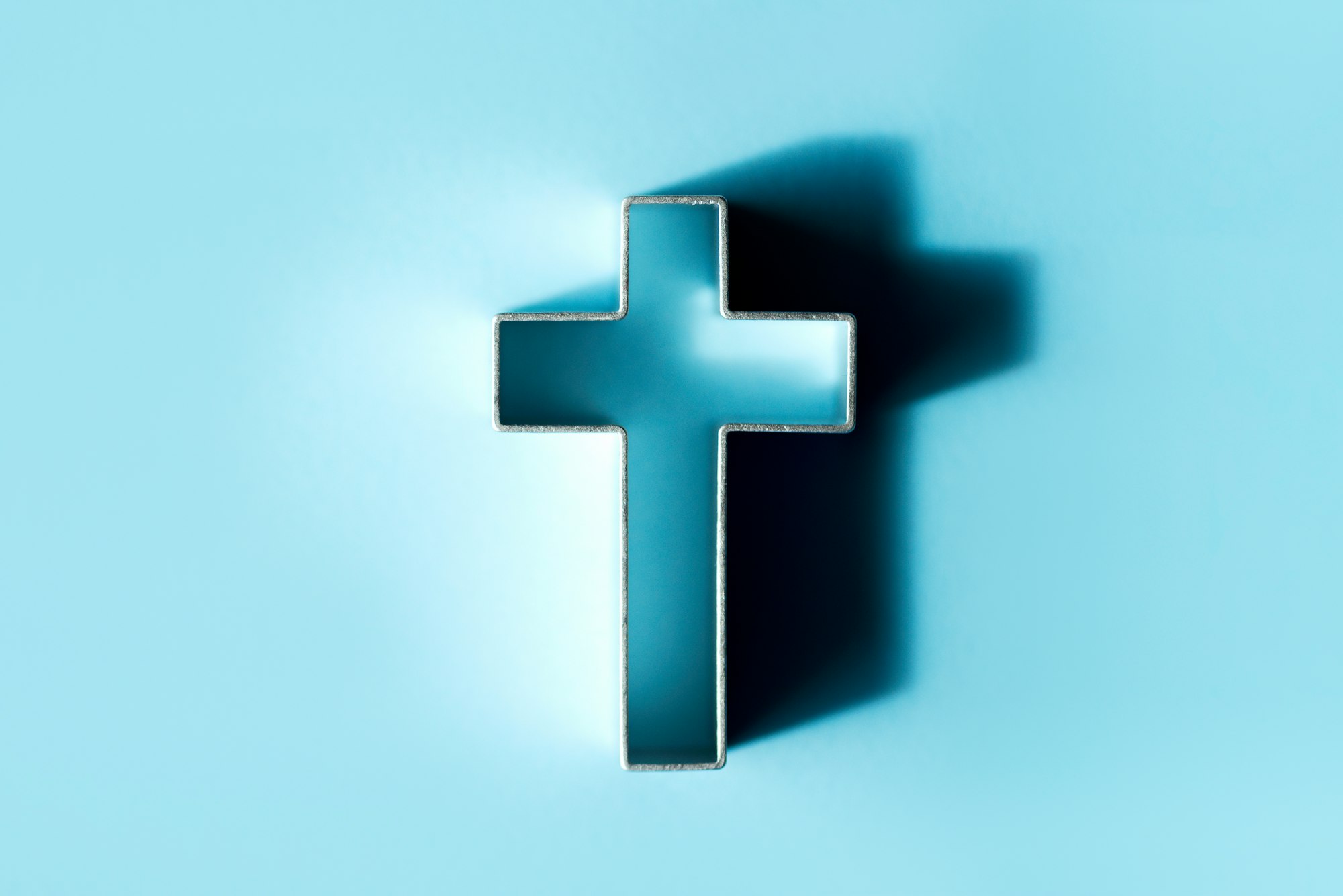 Silhouette of christian cross on blue background, soft bokeh lights background. Copy space. Church