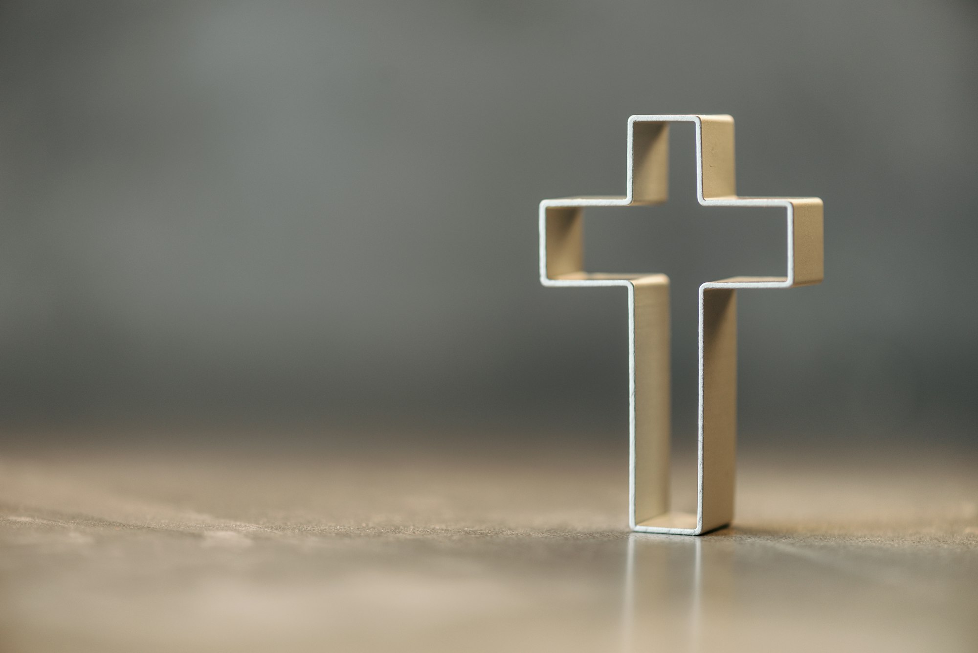 Silhouette of christian cross on grey background, soft bokeh lights background. Copy space. Church